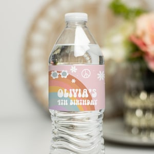 May include: A pink and rainbow water bottle label with the text "Olivia's 4th Birthday" and peace sign and flower graphics.