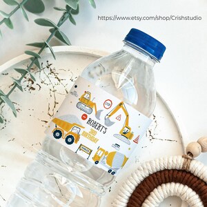 May include: A clear plastic water bottle with a yellow and blue construction vehicle themed label. The label says "Roberts 3rd Birthday".