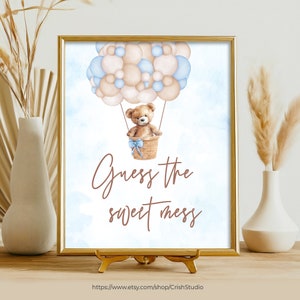 May include: A printable sign with a watercolor illustration of a teddy bear in a hot air balloon made of blue and brown balloons. The sign says "Guess the sweet mess".