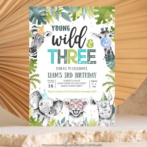 May include: A white invitation with green and blue accents. The invitation is for a child's third birthday party with the theme "Young Wild & Three". The invitation features a zebra, giraffe, elephant, lion, and rhinoceros. The invitation includes the date, time, and location of the party.