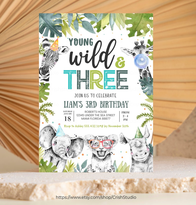 May include: A white invitation with green and blue accents. The invitation is for a child's third birthday party with the theme "Young Wild & Three". The invitation features a zebra, giraffe, elephant, lion, and rhinoceros. The invitation includes the date, time, and location of the party.
