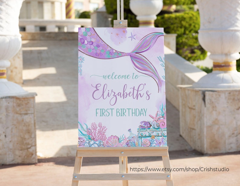 Pu&ograve; includere: Un cartello di benvenuto con una coda di sirena viola e turchese con il testo "Benvenuti al primo compleanno di Elizabeth" su uno sfondo bianco con effetto acquerello.