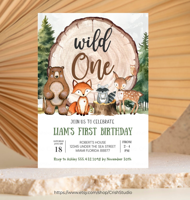 Pode incluir: Uma ilustra&ccedil;&atilde;o em aquarela de animais da floresta, incluindo um urso, uma raposa, um guaxinim e um veado, que cercam um tronco de &aacute;rvore com o texto "wild one" nele. O convite &eacute; para o primeiro anivers&aacute;rio do Liam, com detalhes sobre a data, hora, local e informa&ccedil;&otilde;es de RSVP.