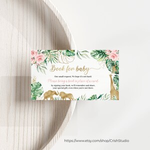 May include: A baby shower invitation card with a safari theme. The card features gold text that reads "Book for baby" and includes illustrations of a giraffe and elephants. The card is decorated with pink roses and green leaves.