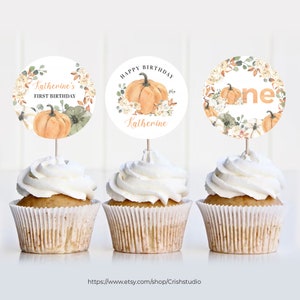 May include: Three cupcake toppers with a fall theme. The toppers feature a pumpkin, fall leaves, and the words "Katherine's First Birthday", "Happy Birthday Katherine", and "One".
