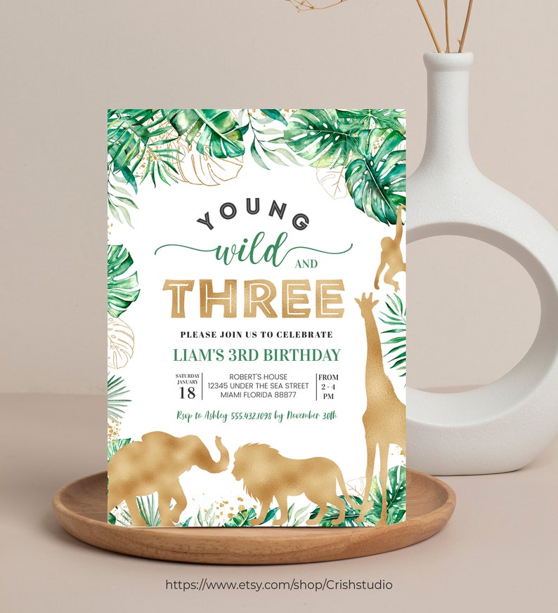 Puede incluir: Una invitaci&oacute;n de cumplea&ntilde;os con tem&aacute;tica de selva con detalles en dorado. La invitaci&oacute;n presenta un fondo de hojas verdes y doradas con un cuadro de texto blanco que dice "Young Wild and Three. Please join us to celebrate Liam's 3rd Birthday." La invitaci&oacute;n tambi&eacute;n incluye una silueta dorada de una jirafa, un mono, un elefante y un le&oacute;n.