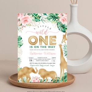 May include: A baby shower invitation with a jungle theme. The invitation features gold foil accents, pink flowers, and green leaves. The text reads "A Little Wild One Is On The Way" and includes event details.