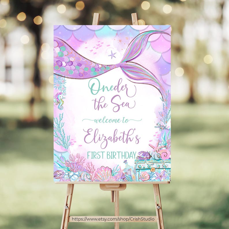 Peut inclure: Une queue de sir&egrave;ne violette et bleue avec un motif de coquillage et d'&eacute;toile de mer. Le texte "Oneder the Sea - welcome to Elizabeth's First Birthday" est sur le panneau.