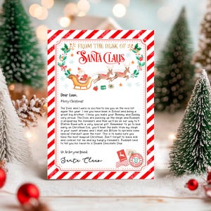 May include: A red and white striped letter from Santa Claus to Liam. The letter is addressed "From the Desk of Santa Claus". The letter includes a drawing of Santa Claus in his sleigh with reindeer. The letter reads, "The Elves and I were so excited to see you on the nice list again this year. I see you have been in School and being a great big brother. I know you make your mummy and Daddy very proud. The Elves are packing up the sleigh and Rudolph is preparing the reindeer and then we'll be on our way to 4 Station Road with a very special gift. Remember to go to bed early on Christmas Eve, you'll hear the bells from my sleigh in your sweet dreams and I shall ask Blitzen to sprinkle some special stardust upon the roof. This is to make sure you have the most magical Christmas. Don't forget to leave milk and cookies for me and my hungry reindeer. Rudolph said to tell you his favourite is Double Chocolate Chip."