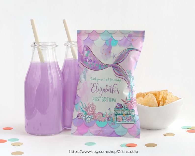 Pu&ograve; includere: Un sacchetto per feste a tema sirenetta in viola e blu con una coda di sirena, conchiglie e uno scrigno del tesoro. Il sacchetto dice "Grazie mille per essere venuto al primo compleanno di Elizabeth".