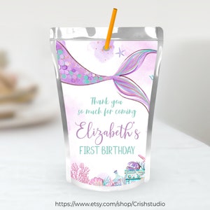 Pu&ograve; includere: Scatola di succo a forma di coda di sirena viola con il testo "Grazie per essere venuto al primo compleanno di Elizabeth" e una stella marina e conchiglie.
