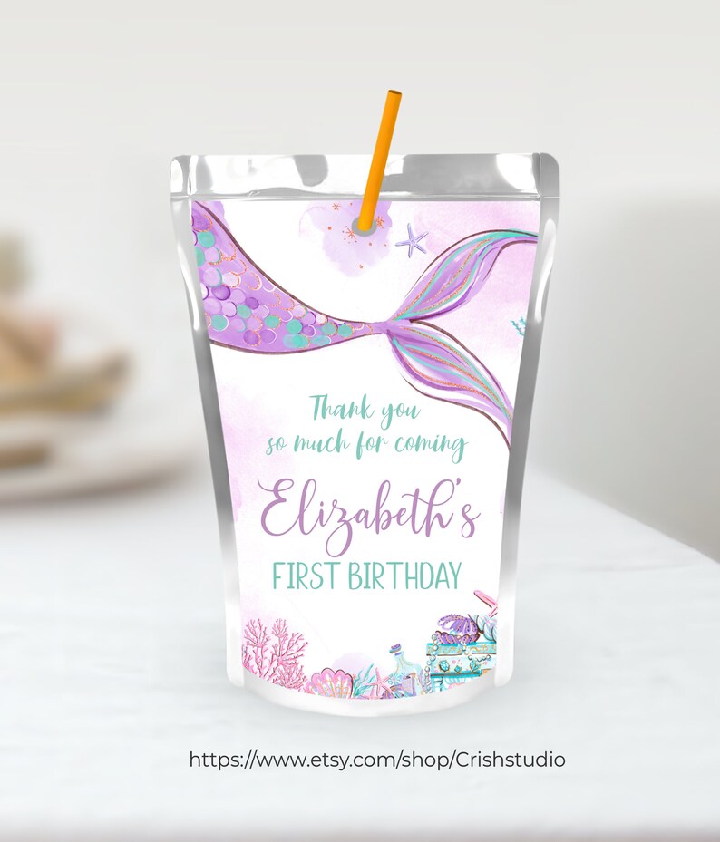 Pu&ograve; includere: Scatola di succo a forma di coda di sirena viola con il testo "Grazie per essere venuto al primo compleanno di Elizabeth" e una stella marina e conchiglie.