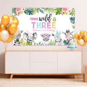 May include: A colorful birthday banner with the text "Young Wild & Three" and the words "Katherine's 3rd Birthday". The banner features a jungle theme with illustrations of animals including an elephant, a zebra, a rhino, and a giraffe.