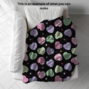 May include: A black throw blanket with a repeating pattern of pink, green, and white candy hearts. The hearts have various phrases printed on them, including "Good Girl", "Slow Burn", "Smut Slut", and "Trigger Warning".