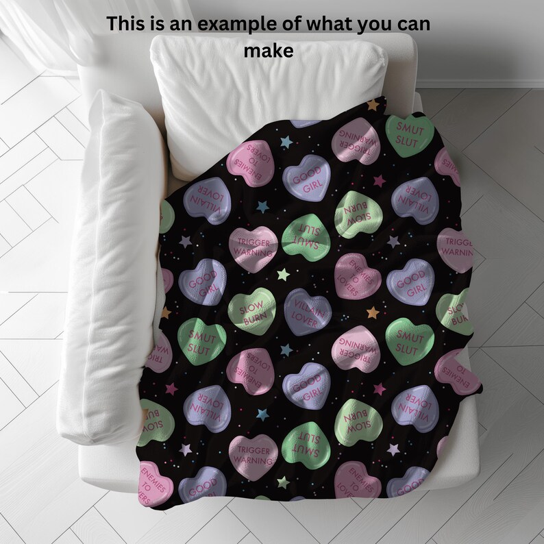 May include: A black throw blanket with a repeating pattern of pink, green, and white candy hearts. The hearts have various phrases printed on them, including "Good Girl", "Slow Burn", "Smut Slut", and "Trigger Warning".