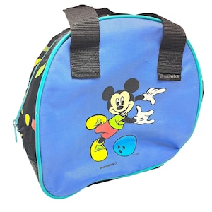 Puede incluir: Una bolsa de bolos azul con un gr&aacute;fico de Mickey Mouse con camisa verde y zapatos amarillos, junto a una bola de bolos azul. La bolsa tiene laterales de tela negra, asas negras y el nombre de la marca Brunswick impreso en blanco en el frente.