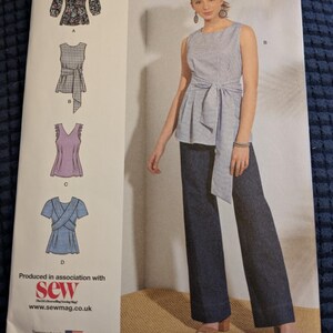 May include: Simplicity sewing pattern K8921, offering designs for women's tops. The pattern includes a selection of styles, including a wrap top, a tie-waist top, and a V-neck top. The size range is U.S. 4-12.
