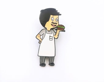 Könnte beinhalten: Eine schwarz-weiße Emaille-Anstecknadel mit einem Cartoon-Charakter, der eine weiße Schürze trägt und einen Hamburger hält. Der Charakter hat schwarze Haare, einen Schnurrbart und ein breites Lächeln.