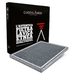 May include: A black box with white text that reads "CUORELAVICO L'AUTENTICA PIETRA LAVICA ETNEA PER UNA CUCINA SALUTARE, SICURA E PRATICA."  The box is next to a gray, square, textured cooking stone with white trim.