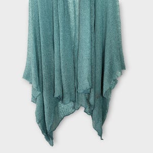 May include: A teal-coloured, open-front cardigan with a textured knit. The lightweight garment has a draped design with asymmetrical edges. The fabric appears soft and flowing, suitable for layering.