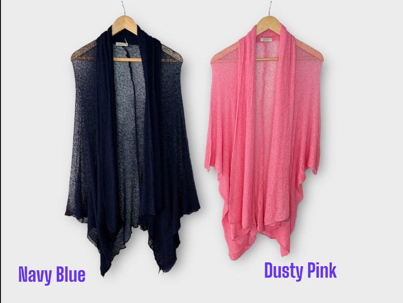May include: Two open-front cardigans, one navy blue and one dusty pink, hang on wooden hangers. The navy blue cardigan is on the left, and the dusty pink one is on the right. The words "Navy Blue" and "Dusty Pink" are written below the cardigans.
