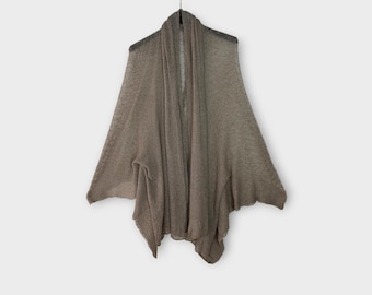 May include: A draped, open-front cardigan in a neutral taupe color hangs against a white background. The lightweight knit fabric has a slightly sheer appearance. The garment is suspended from a black hanger.