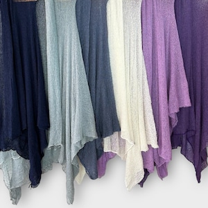 May include: A collection of lightweight, open-front cardigans in various colors, including navy, light blue, white, lavender, and deep purple. The cardigans are displayed hanging, showcasing their flowing, draped design. The fabric appears to be a sheer knit.