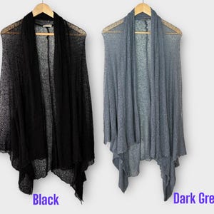 May include: Two open-front cardigans, one black and one dark grey, hang on wooden hangers. The cardigans have a draped design and are made of a lightweight, sheer material. The word "Black" is written below the black cardigan, and "Dark Grey" below the grey one.