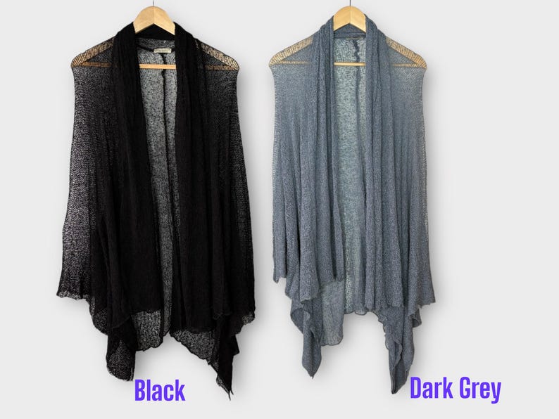 May include: Two open-front cardigans, one black and one dark grey, hang on wooden hangers. The cardigans have a draped design and are made of a lightweight, sheer material. The word "Black" is written below the black cardigan, and "Dark Grey" below the grey one.