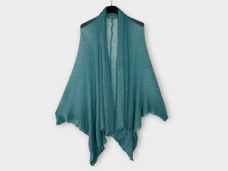 May include: A teal-colored open-front cardigan with a draped design, hanging on a black hanger. The lightweight knit fabric has a slightly textured appearance. The cardigan's asymmetrical hem adds a unique touch to this outerwear.
