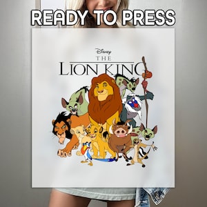 May include: White t-shirt with a print of characters from Disney's The Lion King. The print features Simba, Nala, Timon, Pumbaa, Zazu, and Scar. The text "Disney The Lion King" is printed above the characters.
