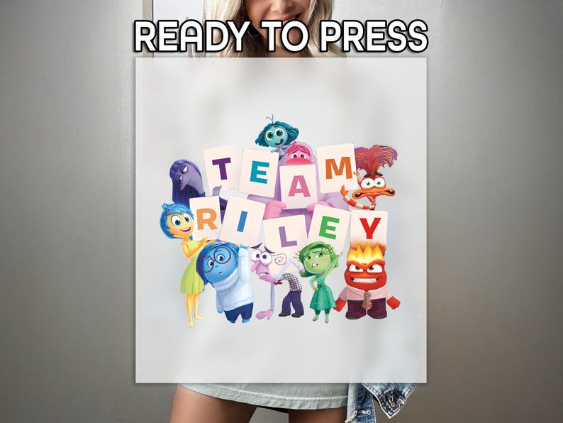 May include: White sublimation print featuring characters from the movie Inside Out. The words "READY TO PRESS" are at the top. The phrase "TEAM RILEY" is spelled out with individual letter cards, surrounded by the movie's characters.