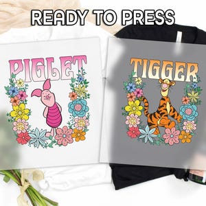 May include: Two iron-on transfers featuring Winnie the Pooh characters Piglet and Tigger. Piglet is pink and has a flower crown. Tigger is orange and black with a flower crown. Both transfers have the text "READY TO PRESS" at the top.