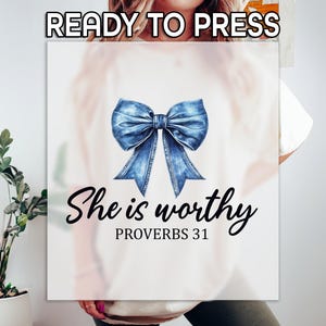 May include: A white t-shirt with a blue denim bow and the text "She is worthy Proverbs 31".