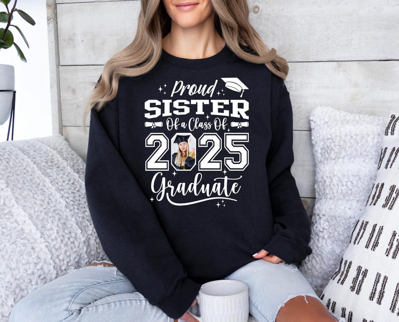 May include: Black sweatshirt with white text that reads "Proud Sister of a Class of 2025 Graduate". A photo of a graduate is in the center of the text.