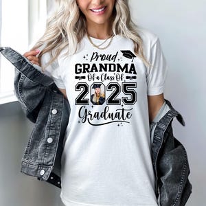 May include: White t-shirt with black text that reads "Proud Grandma of a Class of 2025 Graduate". A graduation cap icon is above the word "Proud" and a photo of a graduate is in the number 2025.