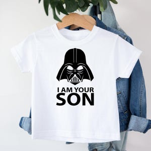 May include: White t-shirt with a black Darth Vader graphic and the text "I am your son".