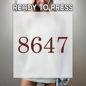 May include: A white rectangular sign with the number 8647 in a dark brown font. The text "READY TO PRESS" is at the top of the sign.