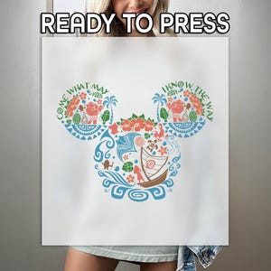 May include: A white t-shirt with a blue and green Mickey Mouse design. The design features a variety of tropical flowers, leaves, and a boat. The text "Come What May" and "I Know The Way" are written around the ears.