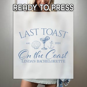 May include: White t-shirt with blue text that reads "Last Toast est. 2024 On the Coast Linda's Bachelorette". The text is surrounded by a seashell, anchor, and a margarita glass.