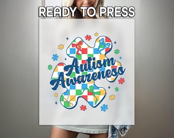 May include: A white t-shirt with a colorful puzzle piece design that says "Autism Awareness".