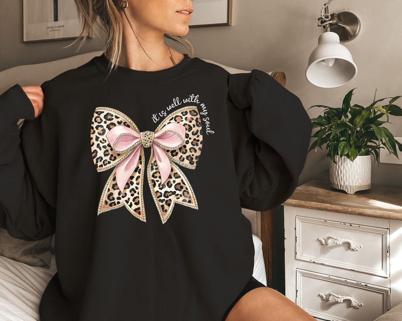 May include: Black sweatshirt with a pink and brown leopard print bow and the text "It is well with my soul".