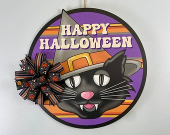 May include: A purple, orange and black Halloween door hanger featuring a black cat wearing a witch's hat with the text "Happy Halloween".