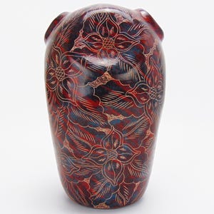 Può includere: Una statuetta di gufo in ceramica rossa e blu con un motivo floreale. Il gufo è scolpito con dettagli intricati e ha una finitura liscia e lucida.