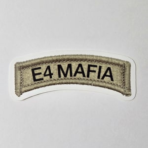 May include: A tan and black embroidered patch with the text "E4 MAFIA" in black block letters. The patch has a curved rectangular shape with a white border and a textured appearance.