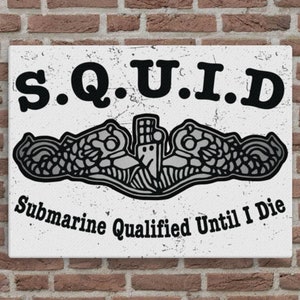 Puede incluir: Un letrero blanco con texto negro que dice "S.Q.U.I.D. Submarine Qualified Until I Die". Un emblema de submarino gris está debajo del texto.