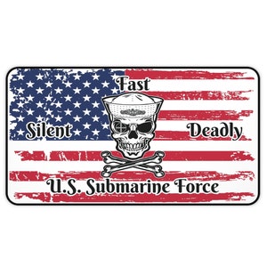 Puede incluir: Una bandera estadounidense desgastada con una calavera con un sombrero de marinero y huesos cruzados. El texto "Fast Silent Deadly U.S. Submarine Force" está impreso debajo de la calavera.