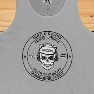 Puede incluir: Una camiseta sin mangas gris claro con un gráfico que presenta una calavera con un sombrero y auriculares navales, con el texto "UNITED STATES SILENT SERVICE DEATH FROM BELOW SUBMARINE FORCE" en un diseño circular. La camiseta sin mangas es de material suave.