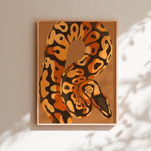 Peut inclure: Impression d'art encadrée représentant une illustration stylisée d'un python royal. Le serpent est représenté dans des tons orange, noir et marron sur un fond beige. L'œuvre est encadrée dans un cadre marron clair.