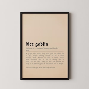 May include: Framed print with the words "dice goblin" in a gothic font. The definition of "dice goblin" is below the title, describing a player who collects dice. The print has a beige background and a black frame.